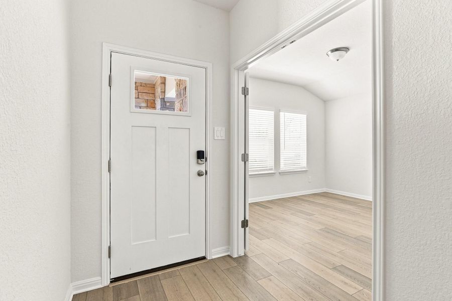 Hardwood floors and crisp white trim create an inviting entryway looking into an adjacent room.