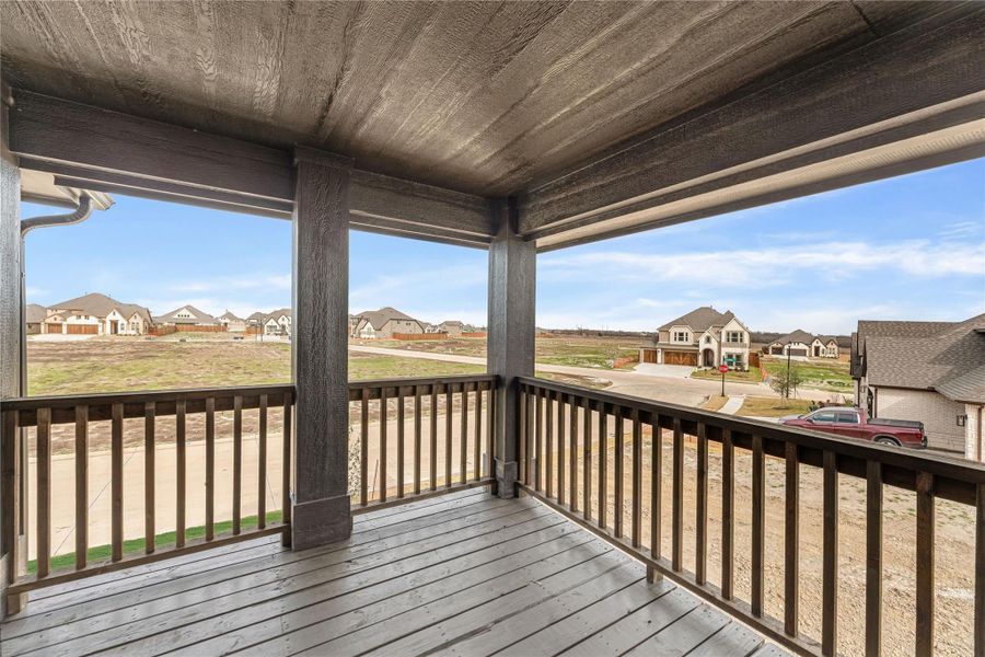 Covered second-floor balcony with wood deck and railing overlooking a new suburban neighborhood Covered second-floor balcony with wood deck and railing overlooking a new suburban neighborhood