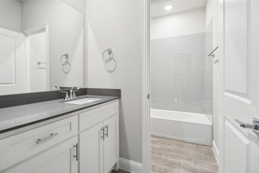 Bathroom with wood-type flooring, vanity, and tiled shower / bath