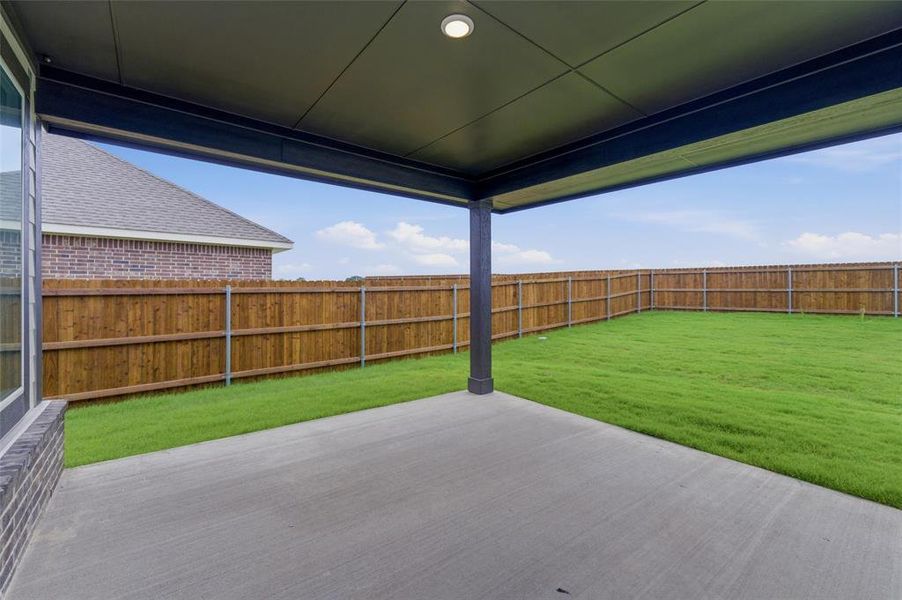 Spacious covered patio with a single recessed light fixture, smooth concrete flooring, and a dark support column