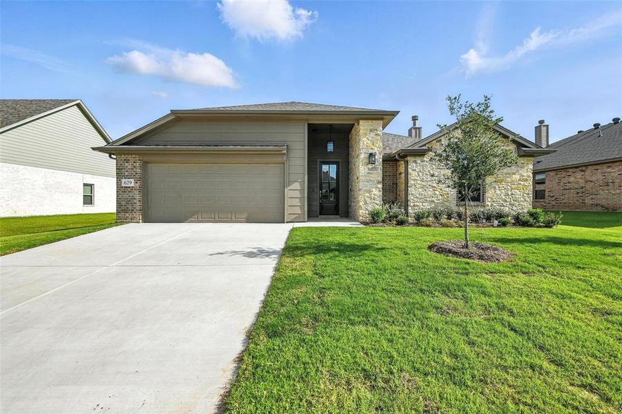 View of front of home featuring concrete driveway, a garage, a front lawn, and stone siding
