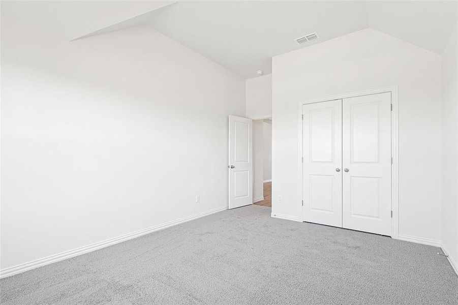 Unfurnished bedroom with carpet floors, a closet, and vaulted ceiling Unfurnished bedroom with carpet floors, a closet, and vaulted ceiling