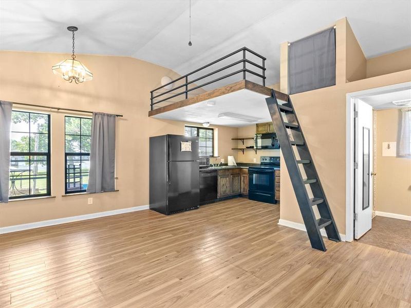 Kitchen featuring black appliances, lofted ceiling, light wood-style floors, open shelves, and dark countertops Kitchen featuring black appliances, lofted ceiling, light wood-style floors, open shelves, and dark countertops