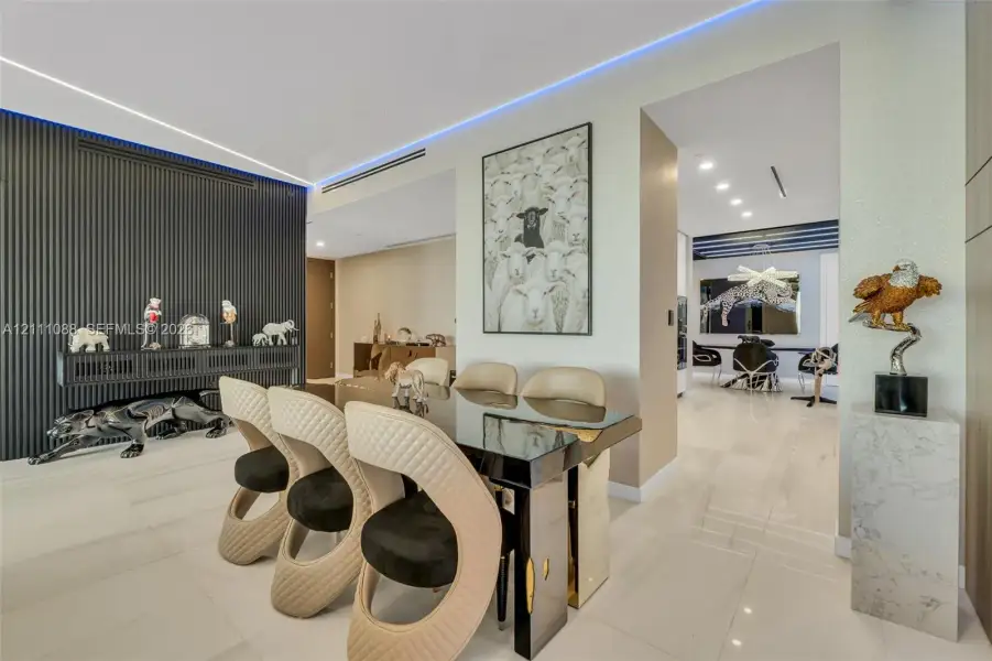Dining area featuring large-format tile flooring, a recessed ceiling with cove LED lighting, and a prominent floor-to-ceiling ribbed accent wall Dining area featuring large-format tile flooring, a recessed ceiling with cove LED lighting, and a prominent floor-to-ceiling ribbed accent wall