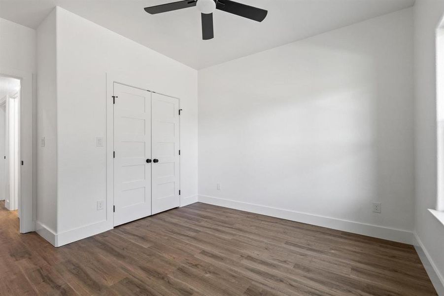 Unfurnished bedroom featuring dark wood-type flooring, ceiling fan, and a closet