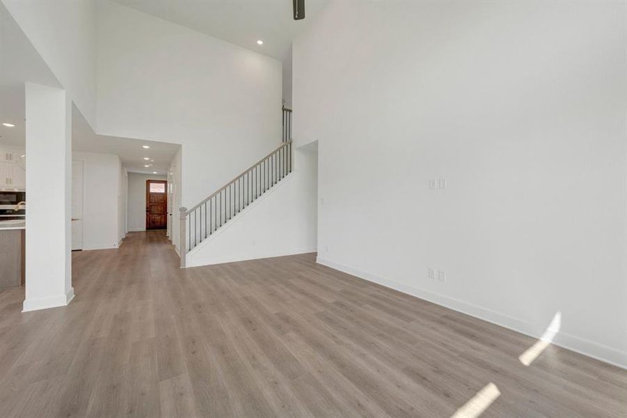 Open-concept living space featuring wood-finish flooring, high vaulted ceilings, and recessed lighting