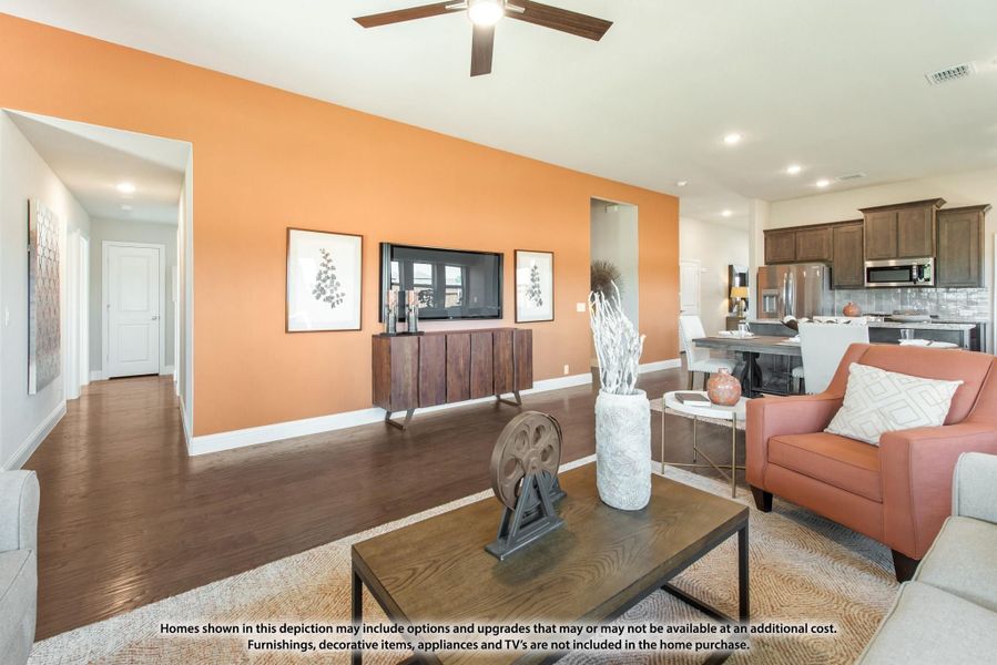 Open living room with orange accent wall, hardwood floors, ceiling fan, and kitchen visible in background Open living room with orange accent wall, hardwood floors, ceiling fan, and kitchen visible in background