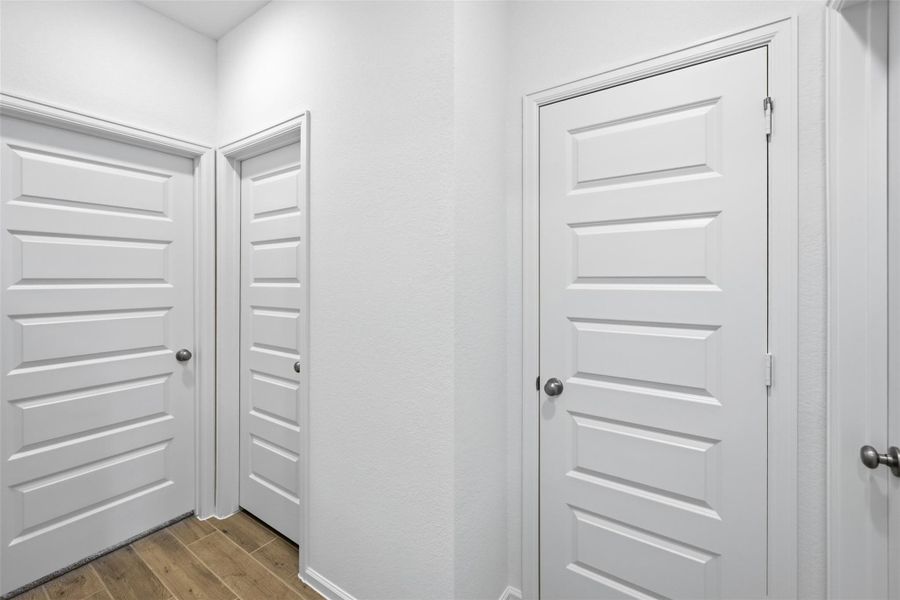 Bright and inviting hallway featuring crisp white paneled doors and elegant wood flooring, offering a modern and clean aesthetic.