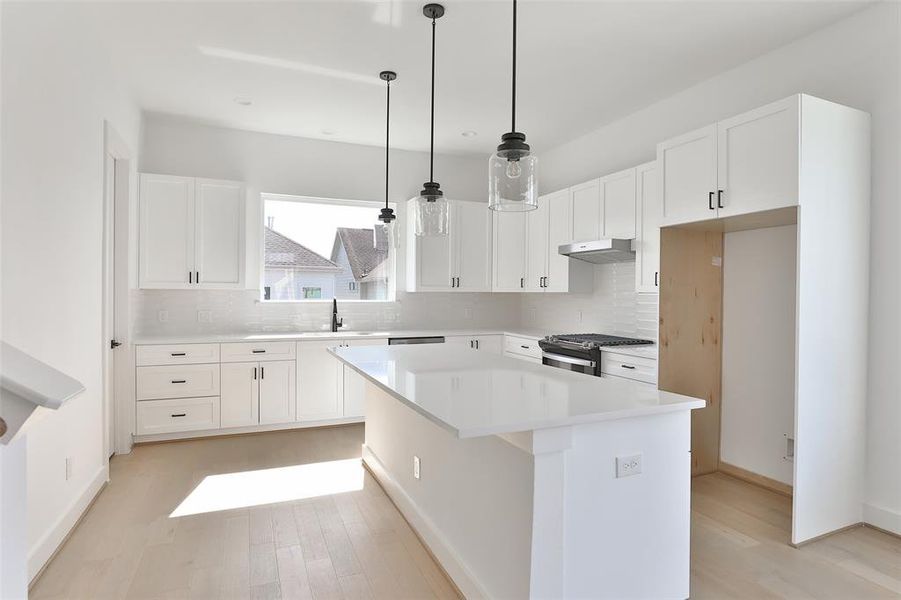 Elegant white quartz countertops complement a bright, all-white kitchen, creating a sleek and contemporary feel. The kitchen island comfortably accommodates 4 barstools, with a built-in microwave seamlessly tucked away for a sleek, uncluttered look.