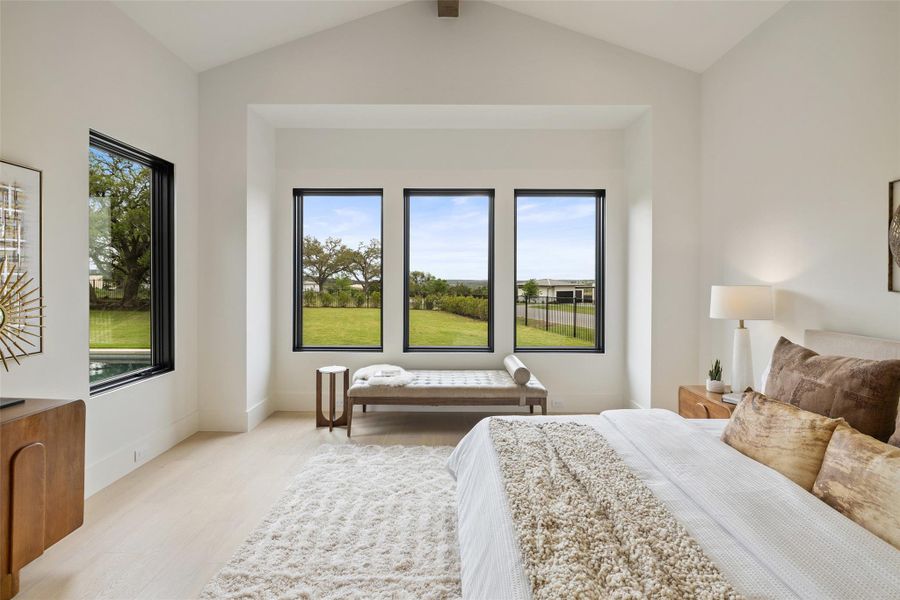 Bedroom featuring baseboards, lofted ceiling, and light wood-style floors Bedroom featuring baseboards, lofted ceiling, and light wood-style floors