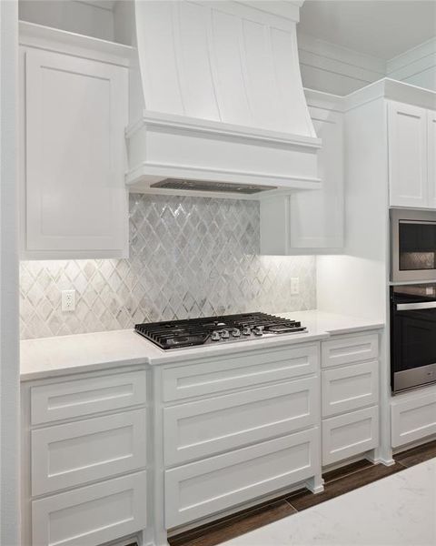 Kitchen featuring white cabinetry, custom exhaust hood, tasteful backsplash, stainless steel appliances, and dark hardwood / wood-style floors