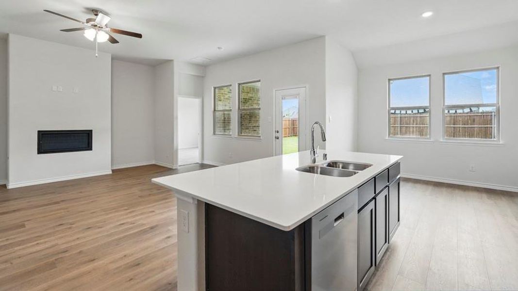 Open concept living space featuring wood-finish flooring, a contemporary fireplace, and an integrated ceiling fan