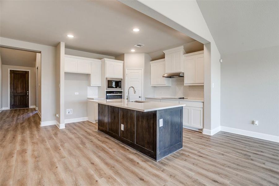 Kitchen with sink, oven, white cabinetry, an island with sink, and built in microwave Kitchen with sink, oven, white cabinetry, an island with sink, and built in microwave