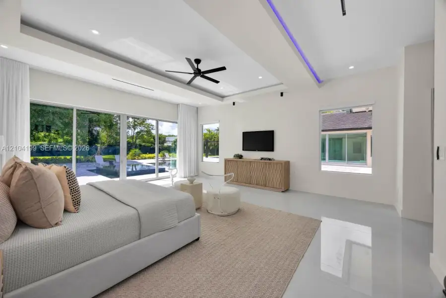 Tray ceiling featuring recessed LED accent lighting, floor-to-ceiling sliding glass doors, polished flooring, a black multi-blade ceiling fan, and recessed can lighting