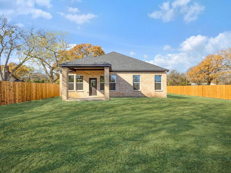 Back of property featuring a fenced backyard, a patio area, a shingled roof, and brick siding