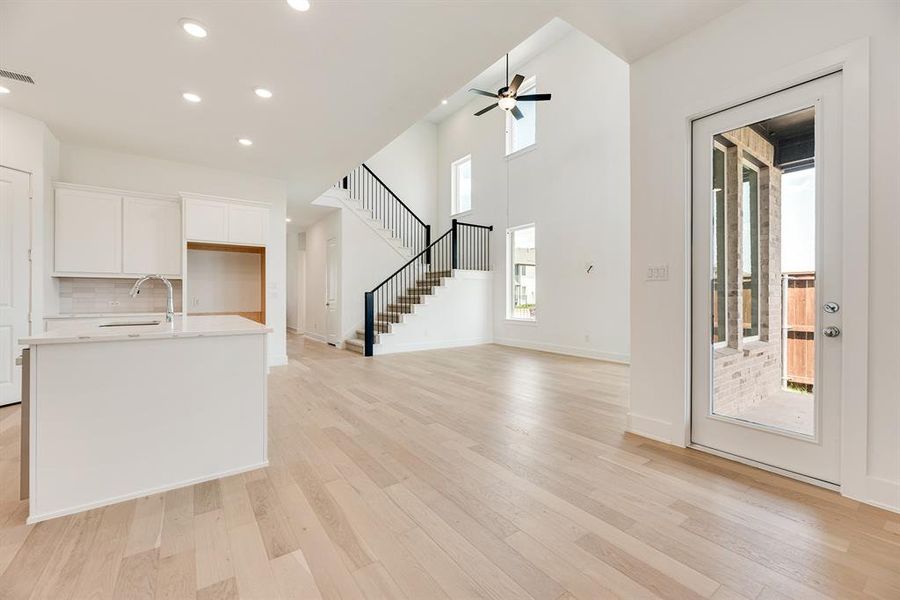 Unfurnished living room featuring recessed lighting, light wood-style flooring, stairway, and ceiling fan Unfurnished living room featuring recessed lighting, light wood-style flooring, stairway, and ceiling fan