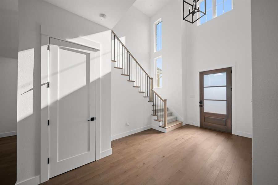 Foyer featuring stairway, hardwood / wood-style floors, and a towering ceiling