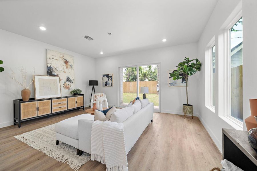 This modern living room features abundant natural light, a cozy layout and tall 10 ft. ceilings. It includes LVP flooring and a view of the fenced backyard through sliding glass doors. This modern living room features abundant natural light, a cozy layout and tall 10 ft. ceilings. It includes LVP flooring and a view of the fenced backyard through sliding glass doors.