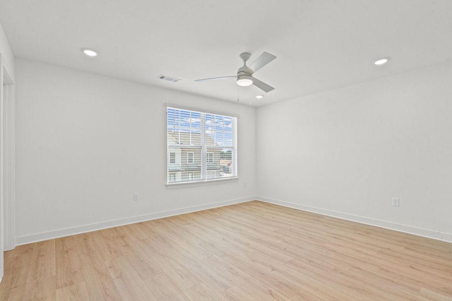 Expansive room with wood-finish flooring, recessed lighting, and a modern ceiling fan