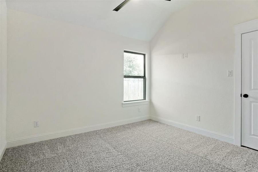 Empty room with lofted ceiling, carpet, and ceiling fan