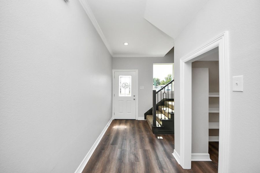Another look at the bright and inviting foyer, featuring an impressive under-stairs niche that adds both charm and practical storage. This thoughtful detail blends style and function, making a great first impression the moment you enter - (representation photo).