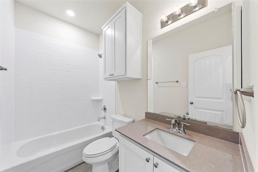 Full bathroom featuring toilet, vanity, and tiled shower / bath