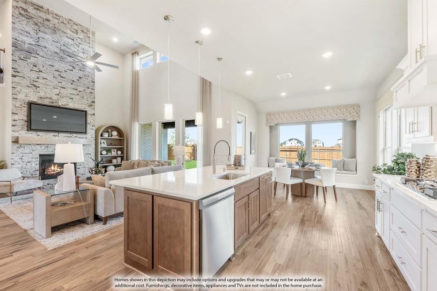 Open-concept kitchen with large island, wood floors, and stone fireplace living room in background Open-concept kitchen with large island, wood floors, and stone fireplace living room in background