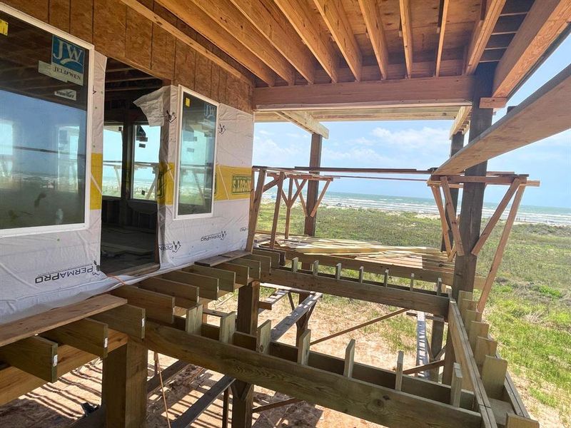 This photo highlights the framing for the upcoming screened-in patio, offering direct access from both the great room and dining area. At the far end, a beachside summer kitchen is planned, providing a shaded spot to grill and entertain while soaking in those ocean views. This photo highlights the framing for the upcoming screened-in patio, offering direct access from both the great room and dining area. At the far end, a beachside summer kitchen is planned, providing a shaded spot to grill and entertain while soaking in those ocean views.