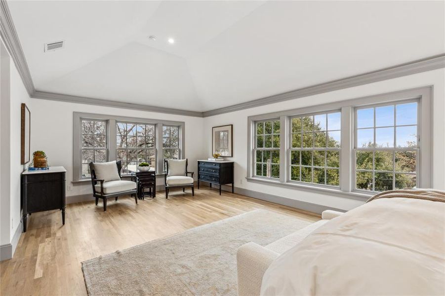 Bedroom with baseboards, visible vents, light wood-style flooring, vaulted ceiling, and crown molding