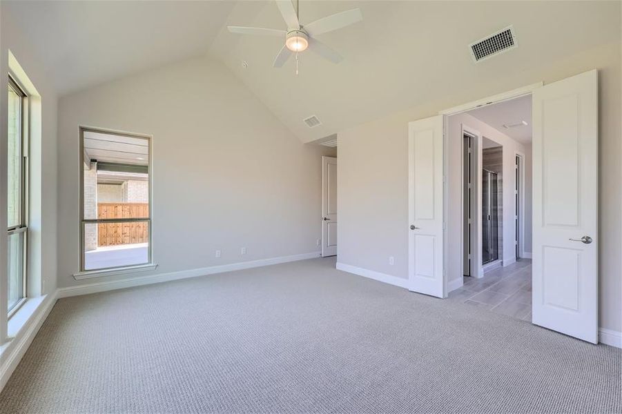 Carpeted empty room with high vaulted ceiling and ceiling fan