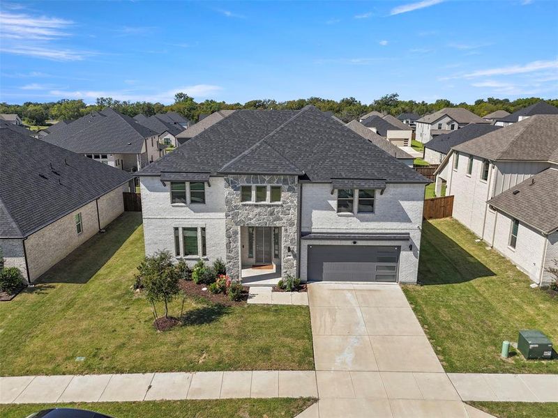 French country style house with a residential view, concrete driveway, stone siding, an attached garage, and brick siding