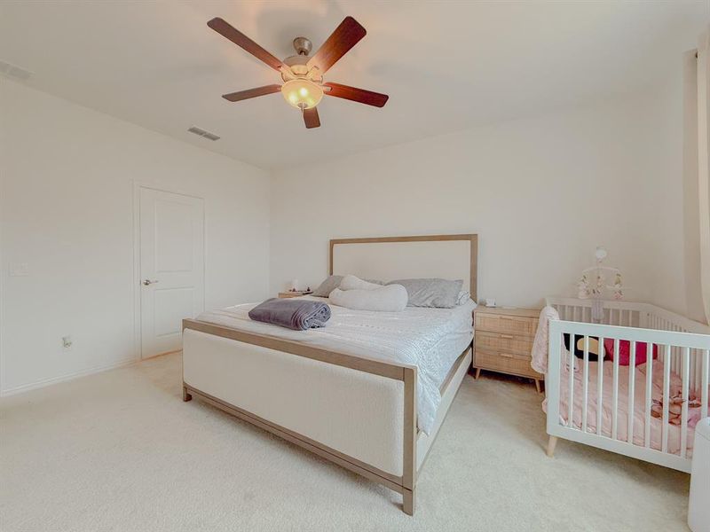 Carpeted bedroom featuring a ceiling fan and visible vents