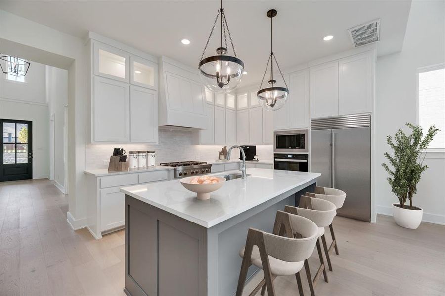Kitchen featuring healthy amount of natural light, built in appliances, white cabinets, and recessed lighting