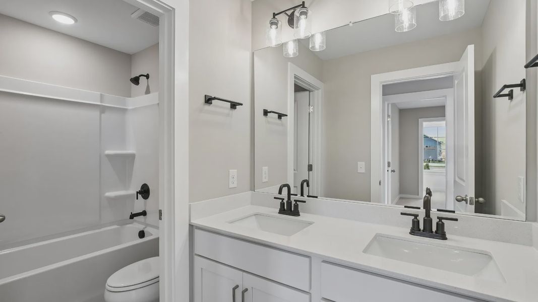 Secondary bathroom with dual vanity and door to shower and toilet Secondary bathroom with dual vanity and door to shower and toilet