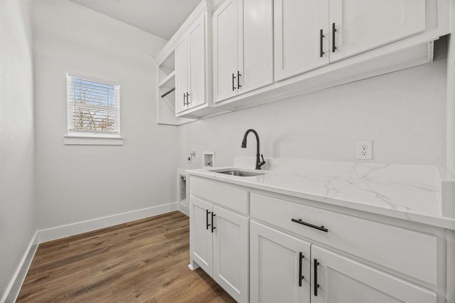 Washroom featuring washer hookup, light wood-style floors, and cabinet space Washroom featuring washer hookup, light wood-style floors, and cabinet space