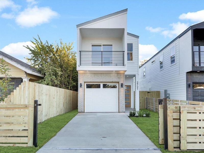 Contemporary home with a balcony, a front yard, and a garage