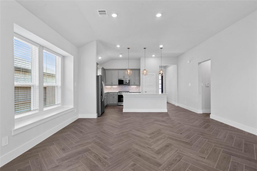 Enjoy meals in this sun-drenched space, featuring durable wood-look tile flooring, large window, window seat for added seating, and recessed lighting.