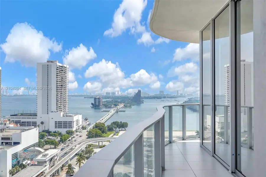 Balcony featuring a glass railing, sliding glass doors, and tile flooring