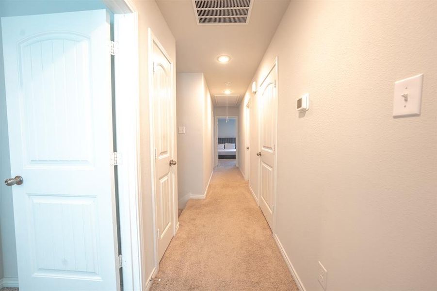 Hallway featuring light carpet and attic access
