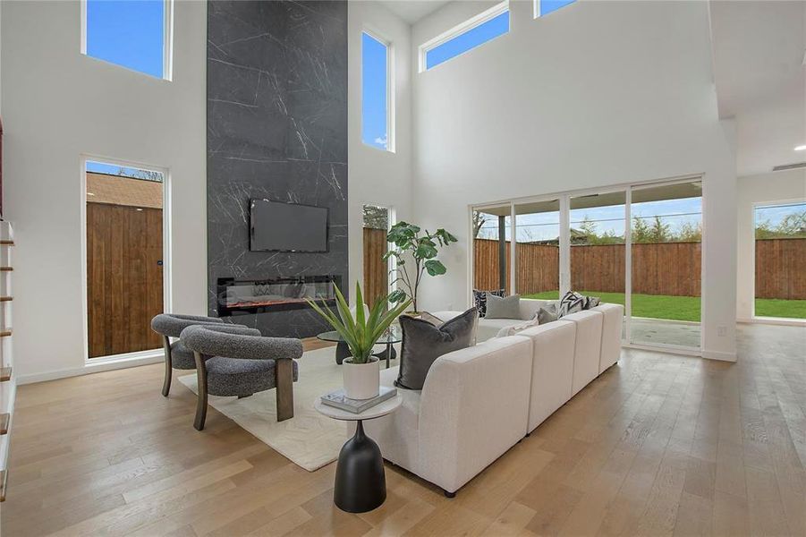 Living room featuring a towering ceiling, a premium fireplace, and light hardwood / wood-style floors