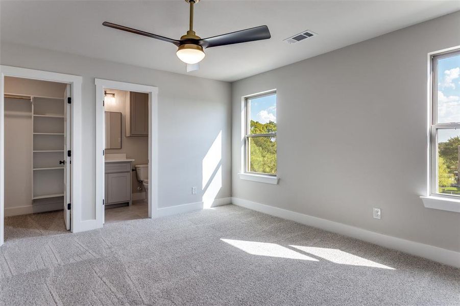 Unfurnished bedroom with light colored carpet, a spacious closet, a ceiling fan, and ensuite bathroom Unfurnished bedroom with light colored carpet, a spacious closet, a ceiling fan, and ensuite bathroom
