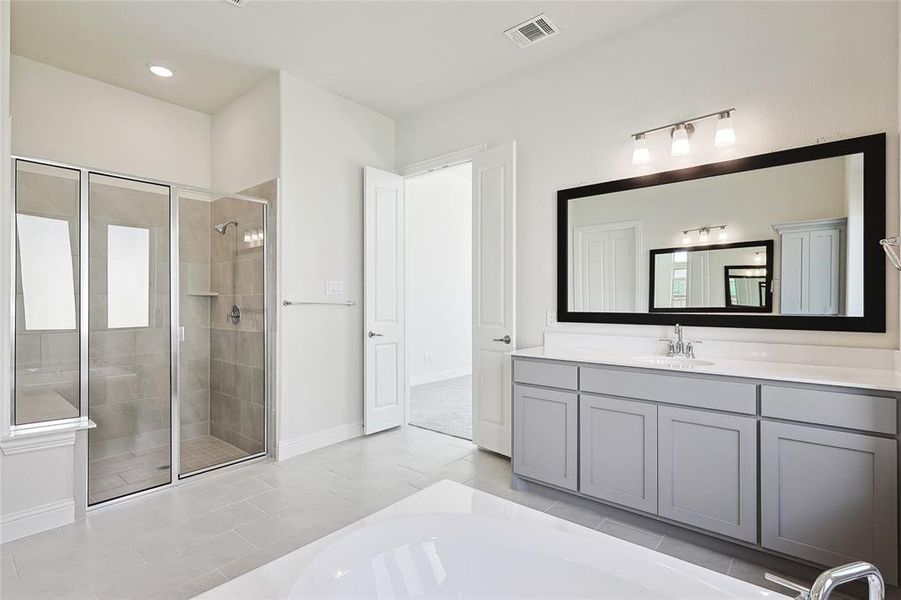 Bathroom featuring tile patterned flooring, shower with separate bathtub, and vanity