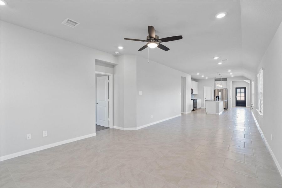 This expansive view from the back of the house showcases a seamless, open-concept layout that creates a warm and inviting path for guests, drawing the eye past the heart of the home toward the welcoming front entryway