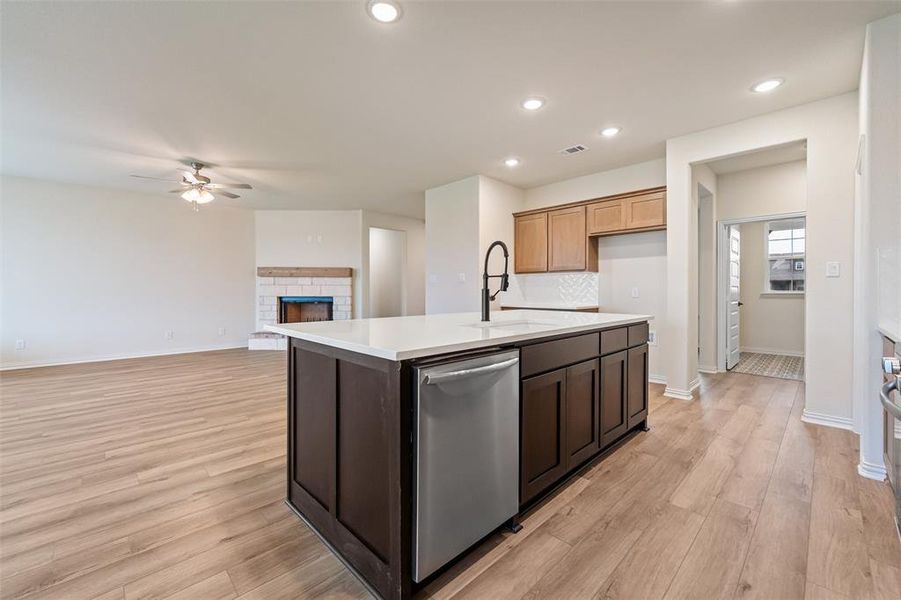 Kitchen featuring stainless steel dishwasher, a center island with sink, light wood-style flooring, a ceiling fan, and recessed lighting