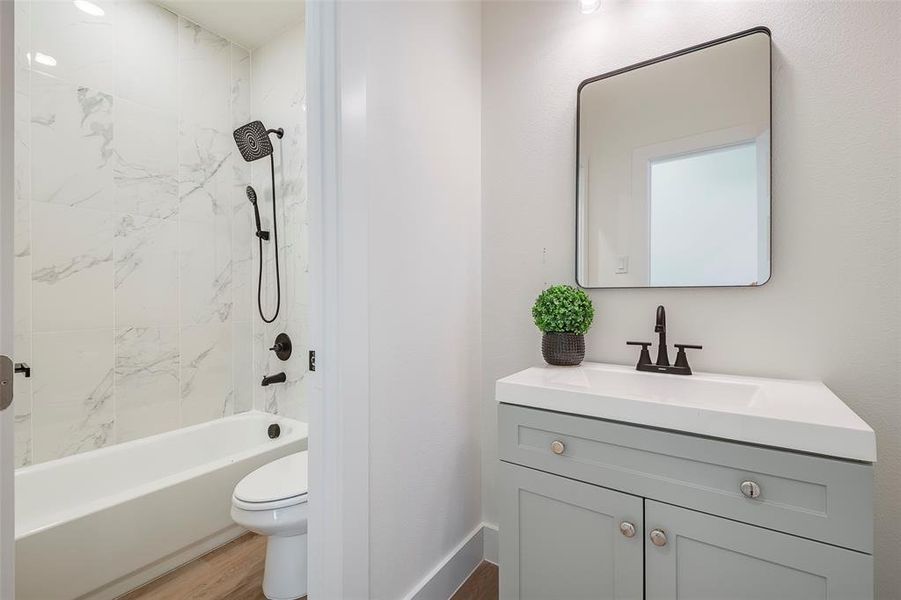 Full bathroom featuring vanity, hardwood / wood-style floors, tiled shower / bath combo, and toilet