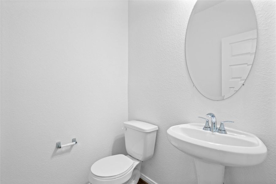 The powder room on the first floor includes a pedestal sink, oval mirror, and toilet to conveniently meet your needs. The powder room on the first floor includes a pedestal sink, oval mirror, and toilet to conveniently meet your needs.