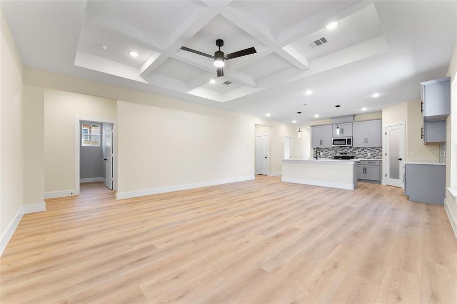 Unfurnished living room with coffered ceiling, beam ceiling, and light hardwood / wood-style floors