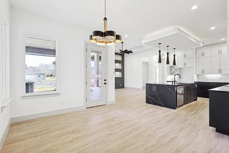 Kitchen featuring pendant lighting, an inviting chandelier, sink, stainless steel dishwasher, and white cabinetry