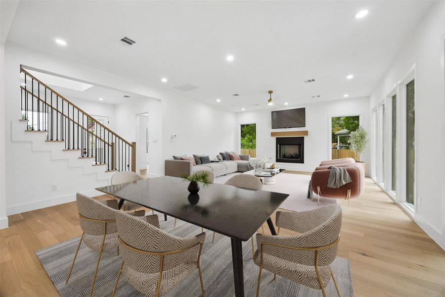 Positioned between the kitchen and living spaces, the dining area creates a natural transition through the center of the home while maintaining open sightlines throughout the main floor. The layout allows the space to function comfortably for daily use while still accommodating larger gatherings, with surrounding windows and rear glass exposures helping carry natural light across the interior. (digitally staged)