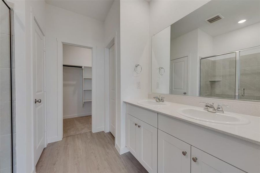 Bathroom featuring a shower with shower door, hardwood / wood-style floors, and dual bowl vanity